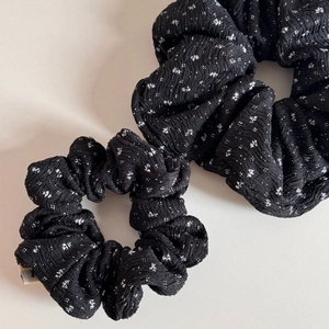 Detailansicht der schwarz-weißen Blumen-Scrunchies mit plissierter Stoffstruktur
