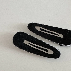 Detail view of black velvet backed metal snap hair clips with silver spring mechanism