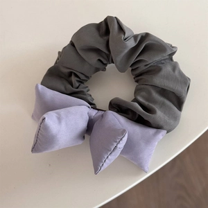 Detailed view of the dark grey scrunchie with a soft purple bow accessory decoration