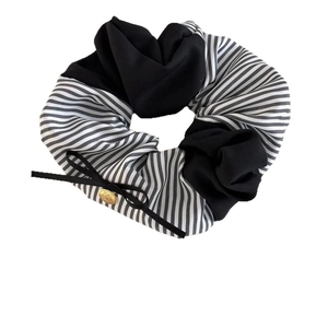 Elegant black and white striped scrunchie with a gold logo charm and bow detail