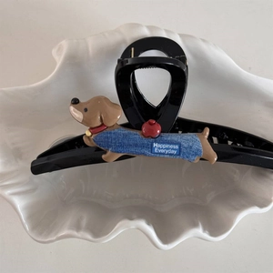 Detail of dachshund hair claw clip on decorative ceramic tray with blue denim vest and apple