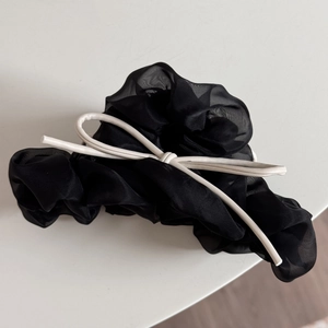 Détail d'un chouchou en tulle noir avec un nœud contrastant en similicuir blanc élégant