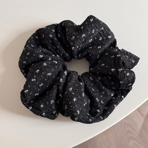 Makro-Detail eines großen Blumen-Scrunchie mit schwarz-weiß gewellter Faltenstoffstruktur