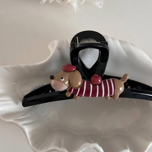 Close-up of a black hair claw clip featuring a cartoon dachshund with a red beret and sweater