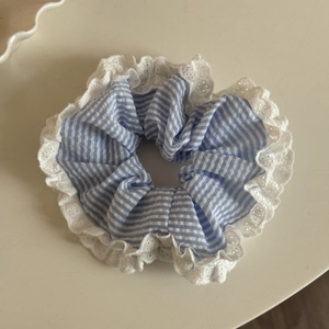 Détail d'un chouchou à rayures bleues avec bordure en dentelle blanche et tissu en coton