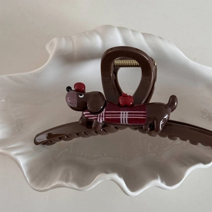 Detail of cute dachshund hair claw clip with red apple decor in a white shell dish