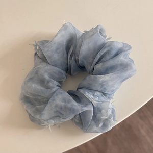 Detalle de coletero de malla azul claro con flores 3D y efecto de teñido degradado