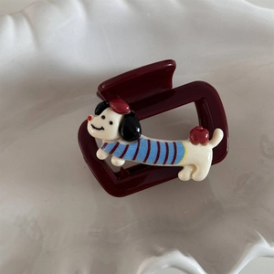 Detail of burgundy square hair claw clip featuring a cute cartoon dachshund wearing a sweater