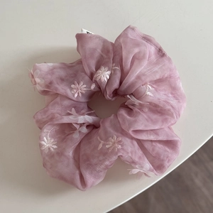 Primer plano de coletero de organza rosa con bordado floral blanco y textura suave