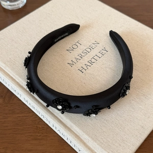 Detail of handmade black sequin floral headband with crystals on a fabric book