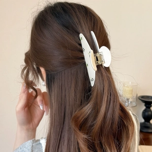 Pince à cheveux chic en acrylique crème à fleurs tenant une coiffure demi-queue élégante