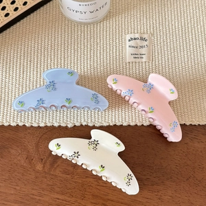 Détails du motif floral sur lot de trois pinces à cheveux en acrylique bleu rose et crème