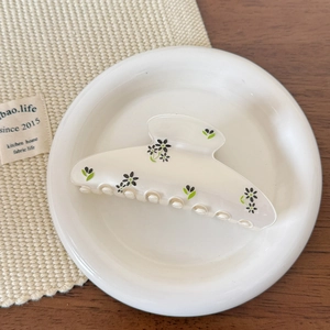 Détail de la pince à cheveux à fleurs crème sur une assiette en céramique élégante