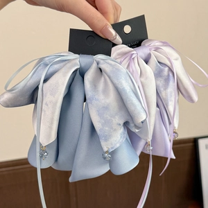 Détail d'une pince à cheveux avec nœud en satin tie-dye, rubans bleus et perles