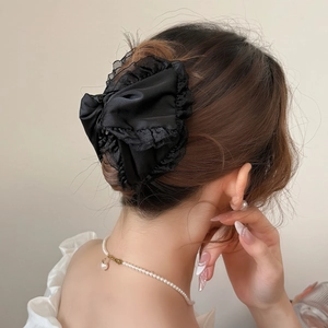 Elegant black satin bow hair claw with mesh lace trim shown on a classic updo hairstyle