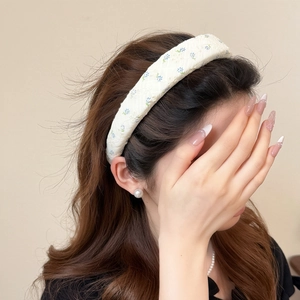 Woman wearing a high-crown blue floral headband with a white base for a stylish look