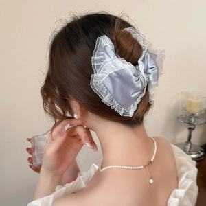 Detail of elegant blue satin hair clip with lace trim on woman's updo hairstyle