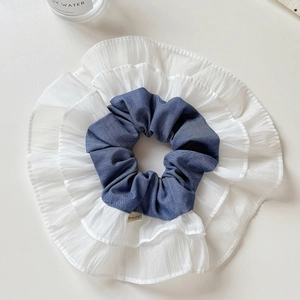 Detail of denim blue cotton and white layered chiffon ruffle scrunchie with soft texture