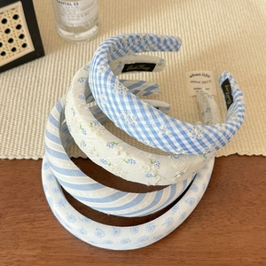 Detail view of four light blue striped and floral embroidered padded headbands on a table