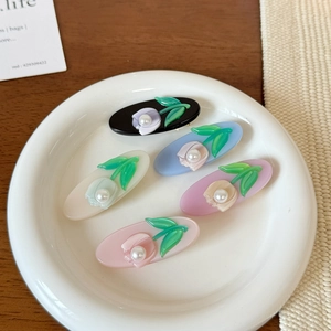 Detailed view of tulip floral resin hair clips with pearls on a ceramic plate