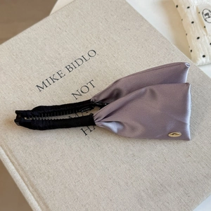 Close-up of purple satin banana hair clip showing smooth fabric texture and gold detail