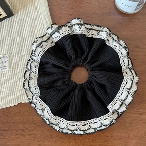Gros plan détaillé d'un grand chouchou plissé noir avec bordure en dentelle blanche