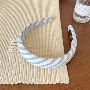 Detailed close-up of blue and white striped fabric headband on a wooden background