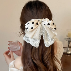 Detailansicht einer gepunkteten Haarschleife mit Spitze und Perlen im Haar der Frau