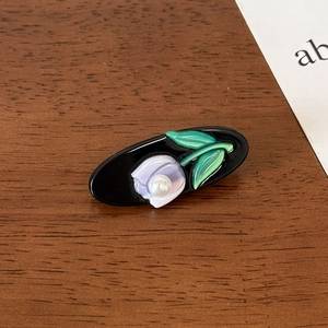 Detail of purple tulip acetate hair clip with white pearl on a rustic wooden table