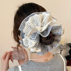 Détail d'un chouchou en dentelle fleurie grise avec broderie sur une coiffure en chignon
