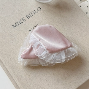 Close-up of pink satin hair accessories with double-layered white lace trim on vintage book