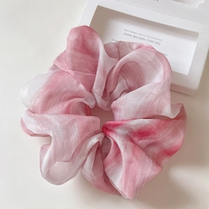 Detailed texture of pink and white gradient chiffon fabric on a luxury hair scrunchie