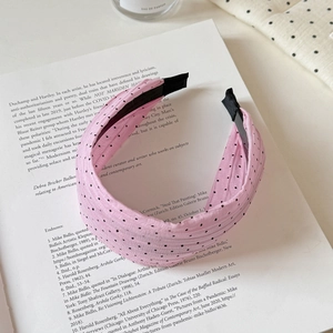 Detailed view of pink polka dot headband fabric with soft pleats on an open book