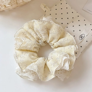 Vue détaillée du chouchou fleuri jaune avec bordure en dentelle et tissu en coton doux