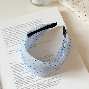 Detail view of light blue polka dot pleated headband on an open book for summer