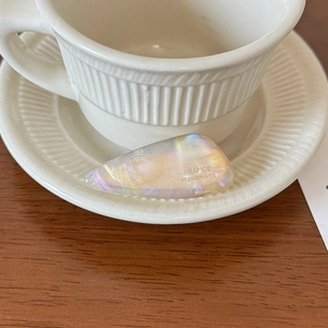 Detailopname van iriserende acetaat haarklem op een elegante keramische schotel