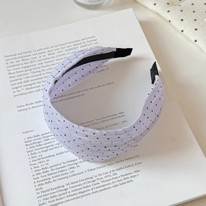 Close-up of light purple polka dot headband with soft fabric texture on a book