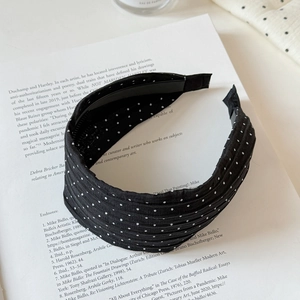 Detail of black wide headband with white dots and non-slip teeth on art magazine