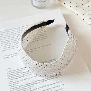 Close-up of wide-brimmed polka dot headband on an open book showing fabric texture