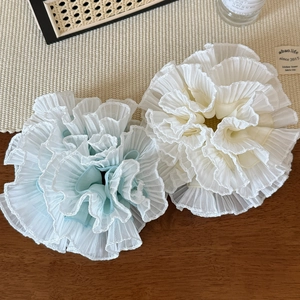 Detail of light blue and beige pleated chiffon hair scrunchies on a wooden surface