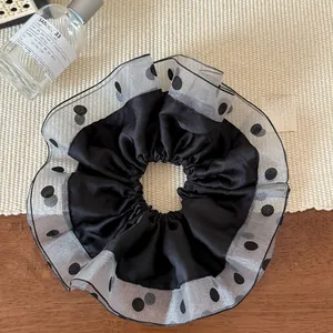 Close-up of mesh polka dot scrunchie with silk satin texture and layered tulle design