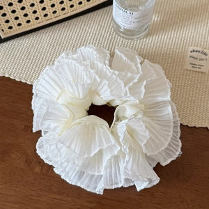 Detail of elegant white pleated scrunchie with layered ruffle texture on wooden table