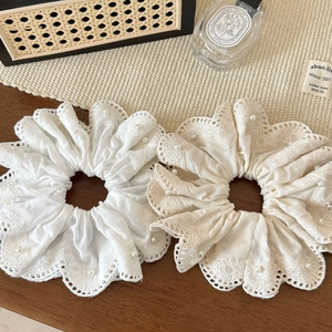 Close-up of beige lace scrunchies with pearl embellishments on a wooden table