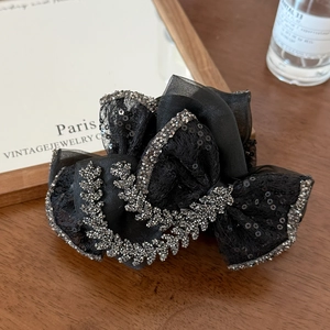 Close-up of elegant black mesh bow hair claw clip with sparkly sequins and rhinestones