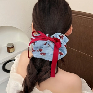 Chouchou à fleurs avec nœud en velours rouge porté sur un chignon haut élégant
