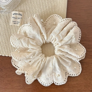 Detailed view of beige lace scrunchie with delicate white pearls on waffle fabric