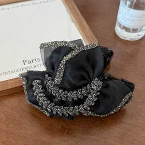 Detail of elegant black ribbon hair claw clip with sparkling rhinestones on fabric edge