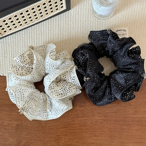 Detailed shot of pleated polka dot scrunchies in black and white with rhinestone trim