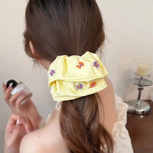 Chouchou oversize jaune pâle avec fleurs en perles colorées porté sur les cheveux