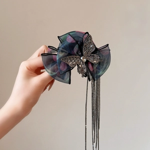 Détail d'une grande pince à cheveux papillon en organza avec strass et longs pompons
